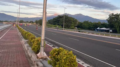 Red-surfaced bike lane along the coastal road at dawn with mountains beyond