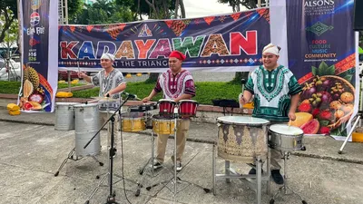 Drummers in traditional dress performing under a Kadayawan festival banner