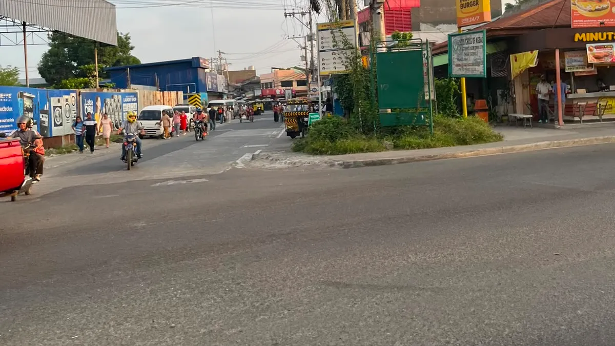 Busy junction with vendors, tricycles and a market spilling toward the road