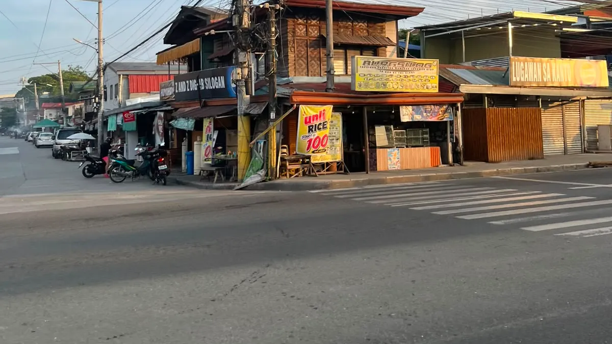 Corner shops advertising rice by the kilo under a dense web of overhead wires