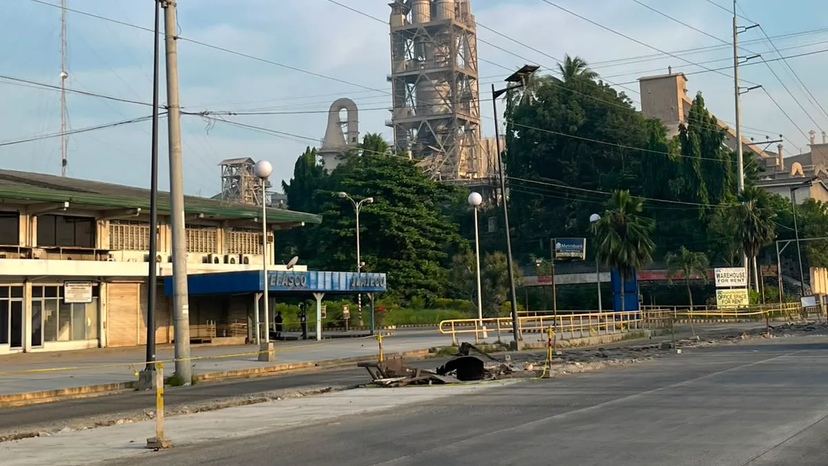 Cement plant towers rising behind a quiet roadside frontage