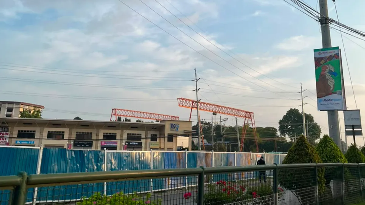 A red gantry crane beside a commercial building under construction in Davao