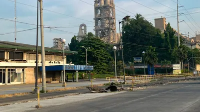 Cement plant towers rising behind a quiet roadside frontage