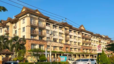 Mid-rise condominium block with tiled roofs and planted balconies seen from the street