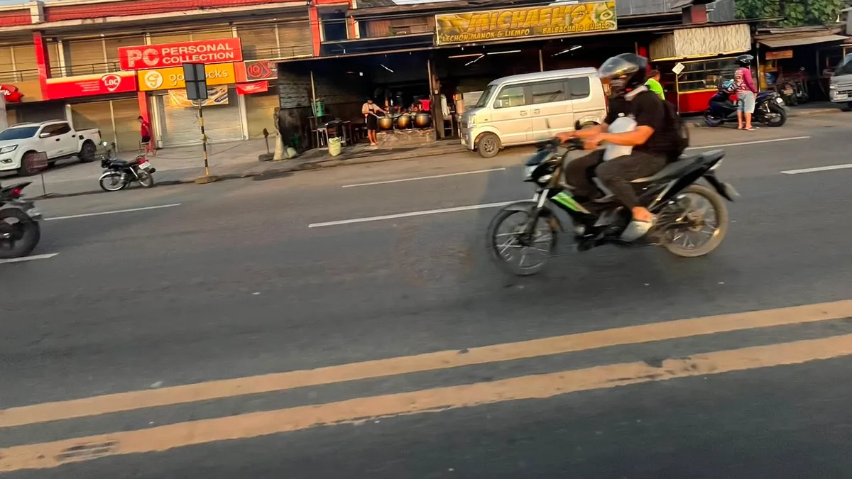 Motorbike blurring past a row of roadside shops