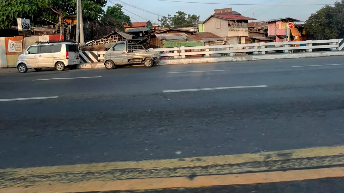 Houses and parked vans behind a white roadside guardrail