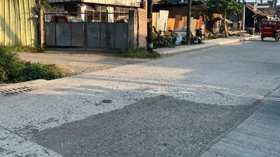 Freshly poured concrete side road running past old timber houses