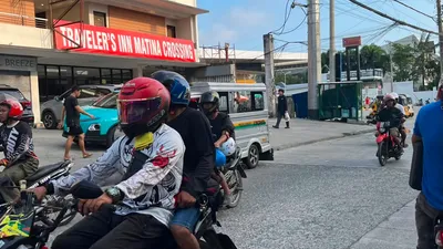 Motorcyclists waiting at Matina Crossing below a traveller's inn sign