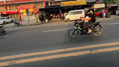 Motorbike blurring past a row of roadside shops