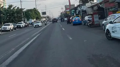 Busy Davao city street lined with shops and parked vehicles in a student rental district