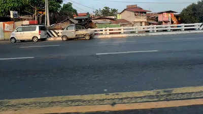 Houses and parked vans behind a white roadside guardrail