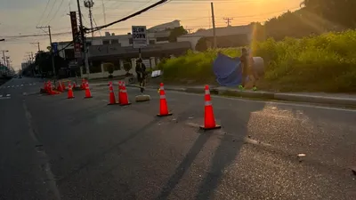 Traffic cones closing a lane at sunrise with long shadows across the asphalt