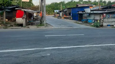 Quiet side-road junction with informal houses and a red tarpaulin awning