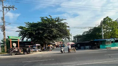 Suburban highway with tricycles waiting outside a row of small shops