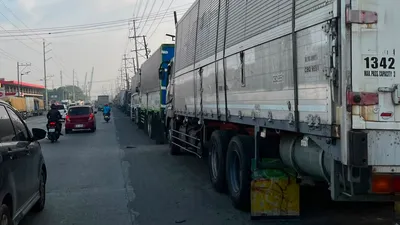 Line of container trucks parked along the highway shoulder